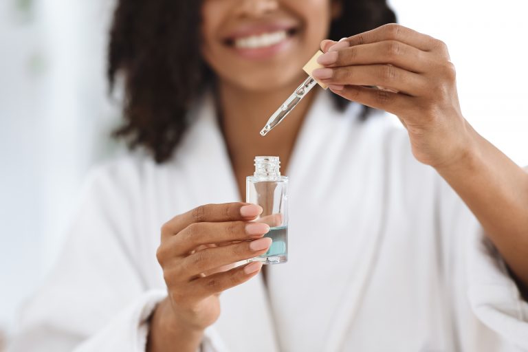 Woman holds skincare product with active Ingredients.