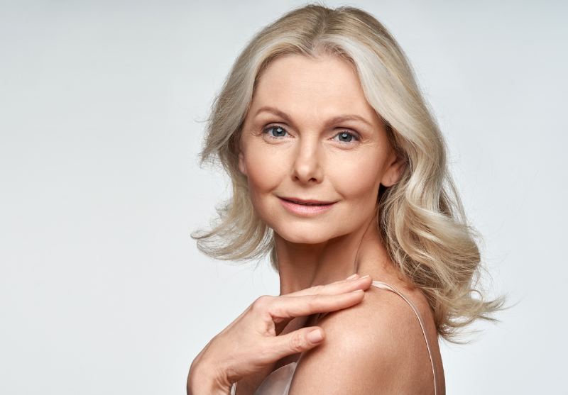Image of older lady looking towards the camera with her hand on her shoulder