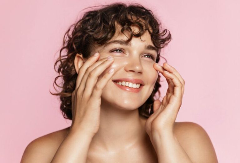 Close up of a young woman on a pink background lookig away from the camera